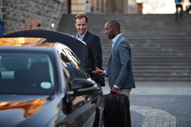 limo service springfield il - Driver assisting businesspeople into cab, at taxi station in early morning